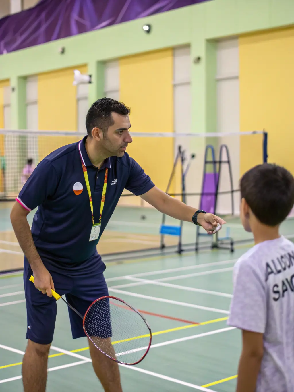 A focused image of a badminton coach providing personalized instruction to a player at LE VOLANT DE L'ALAGNON, emphasizing the importance of expert guidance.